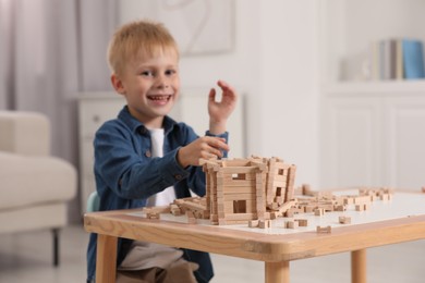 Cute little boy playing with wooden blocks at table indoors, selective focus. Child's toy