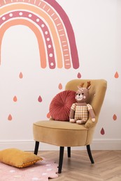 Photo of Child's room interior with comfortable armchair, toy and painting on white wall. Stylish design