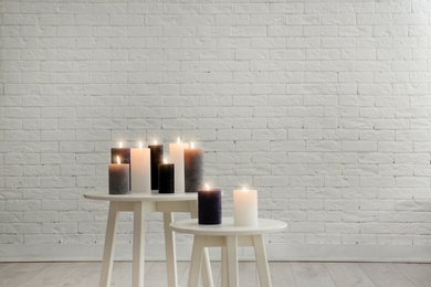 Photo of Burning candles on tables against brick wall with space for text