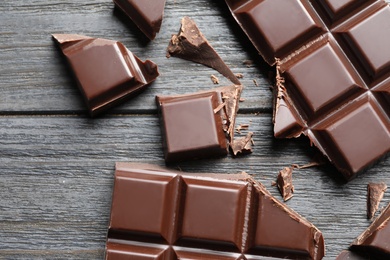 Pieces of chocolate on wooden background, top view