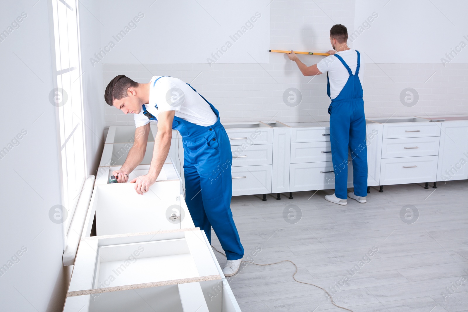 Photo of Maintenance workers installing new kitchen furniture indoors