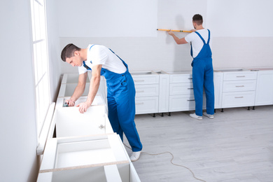 Maintenance workers installing new kitchen furniture indoors