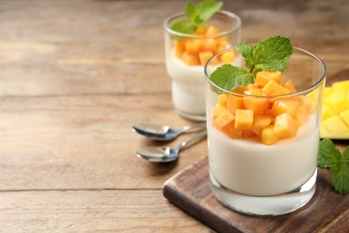 Photo of Delicious panna cotta with mango on wooden table. Space for text