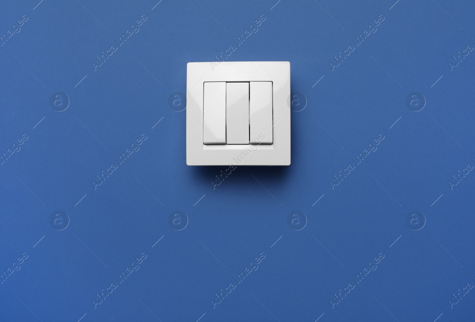 Photo of Modern plastic light switch on blue background. Space for text