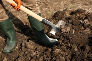 Worker digging soil with shovel outdoors, closeup