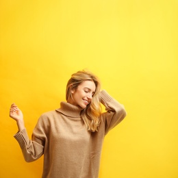 Photo of Beautiful young woman wearing knitted sweater on yellow background