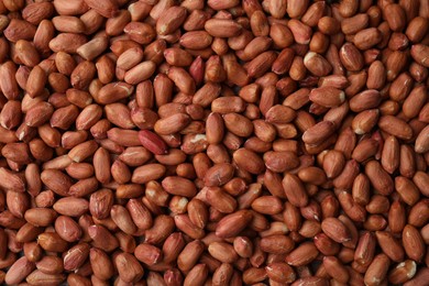 Photo of Many fresh unpeeled peanuts as background, top view