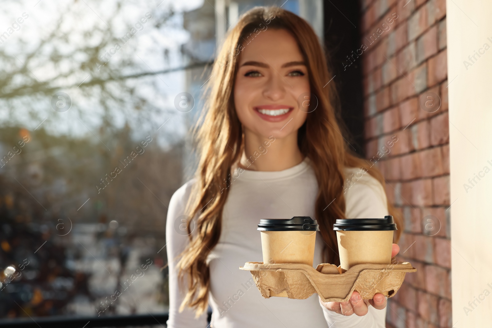 Photo of Happy young woman holding paper coffee cups outdoors, focus on drinks