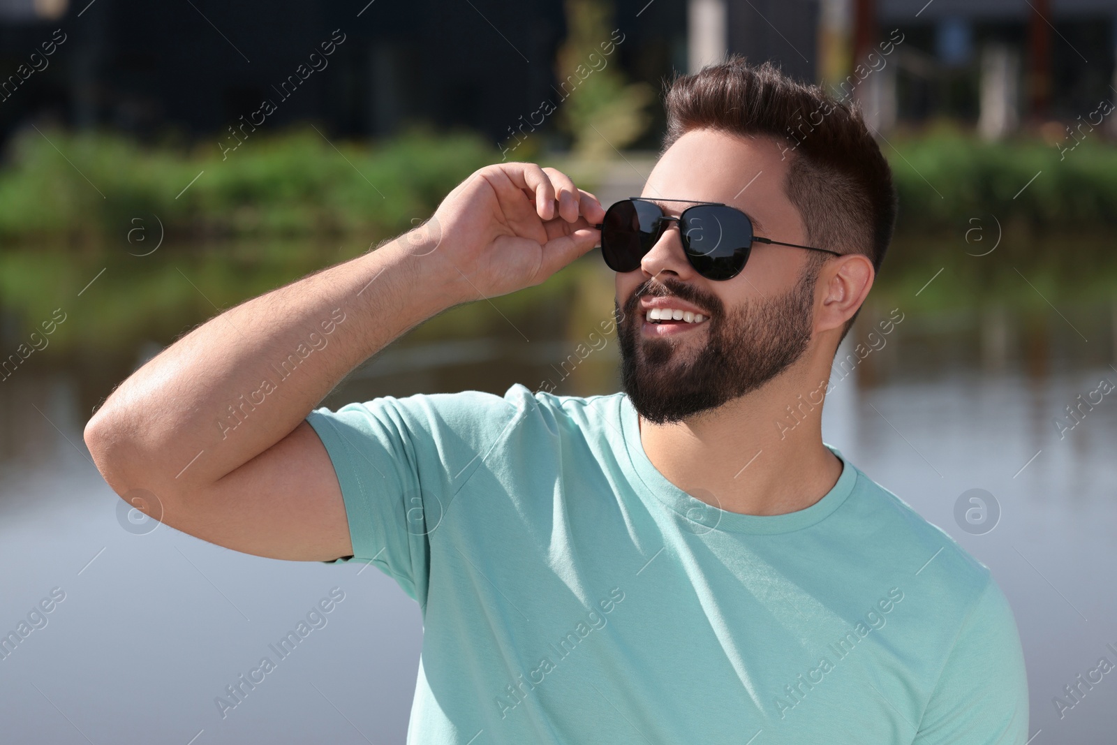 Photo of Handsome smiling man in sunglasses near river