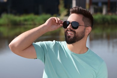 Handsome smiling man in sunglasses near river