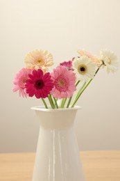 Photo of Vase with beautiful gerbera flowers on wooden table