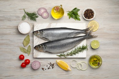 Photo of Delicious salted herrings and different ingredients on light wooden table, flat lay