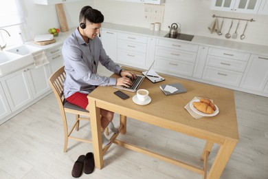 Businessman in shirt and underwear working on laptop at home