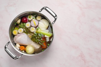 Photo of Different ingredients for cooking tasty bouillon in pot on pink marble table, top view. Space for text