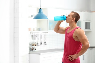 Athletic young man drinking protein shake in kitchen