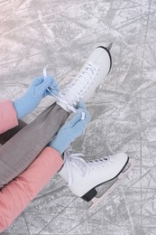 Photo of Woman lacing figure skates on ice, top view