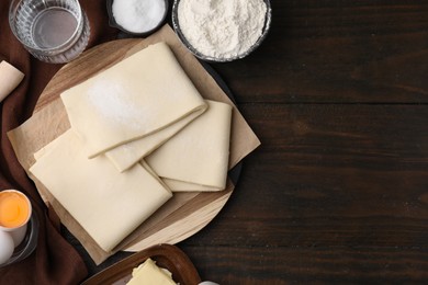 Photo of Raw puff pastry dough and ingredients on wooden table, flat lay. Space for text