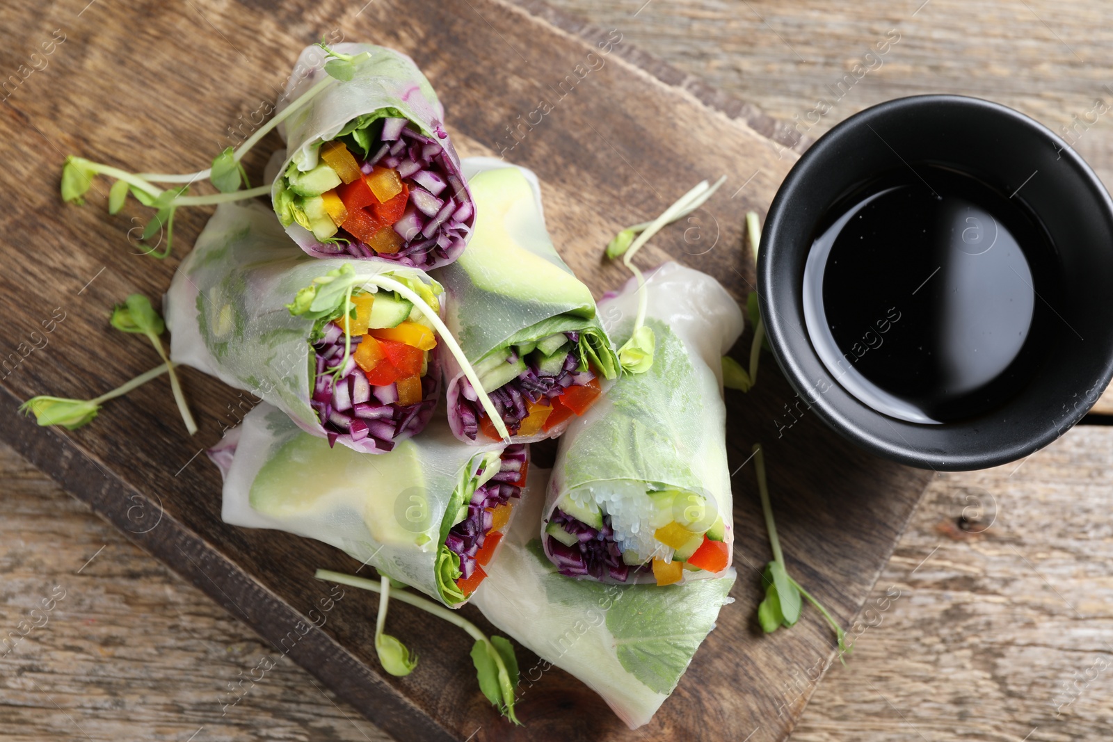 Photo of Delicious spring rolls and soy sauce on wooden table, top view