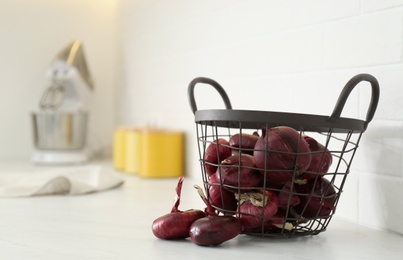 Photo of Basket with red onions on white table. Space for text