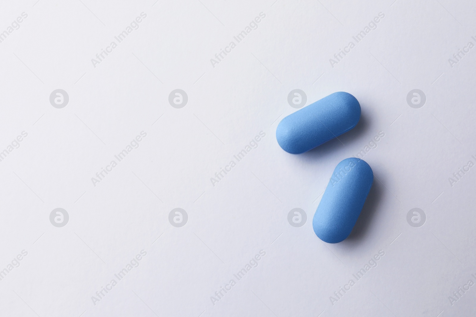 Photo of Pills and space for text on white background, top view. Potency problem