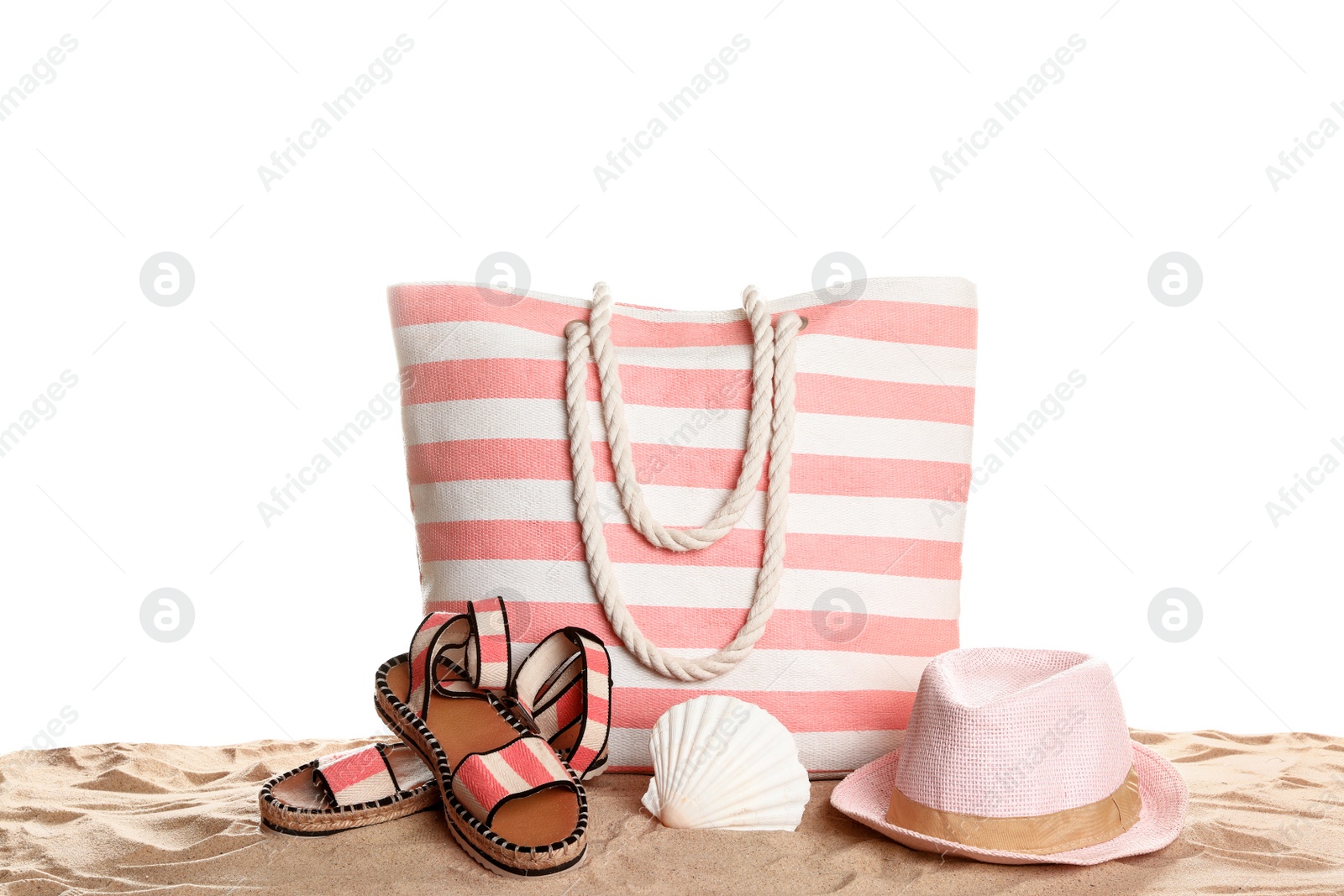 Photo of Stylish striped bag and beach accessories on sand against white background