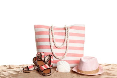 Photo of Stylish striped bag and beach accessories on sand against white background