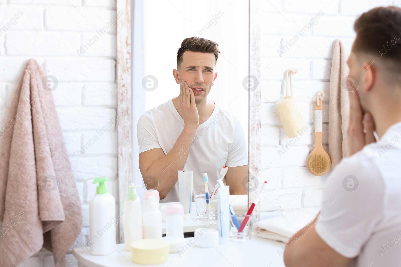 Photo of Young man with sensitive teeth in bathroom