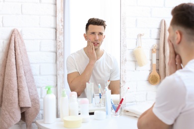 Photo of Young man with sensitive teeth in bathroom