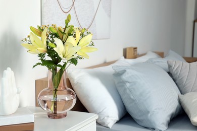 Photo of Vase with bouquet of fresh flowers on white nightstand in bedroom