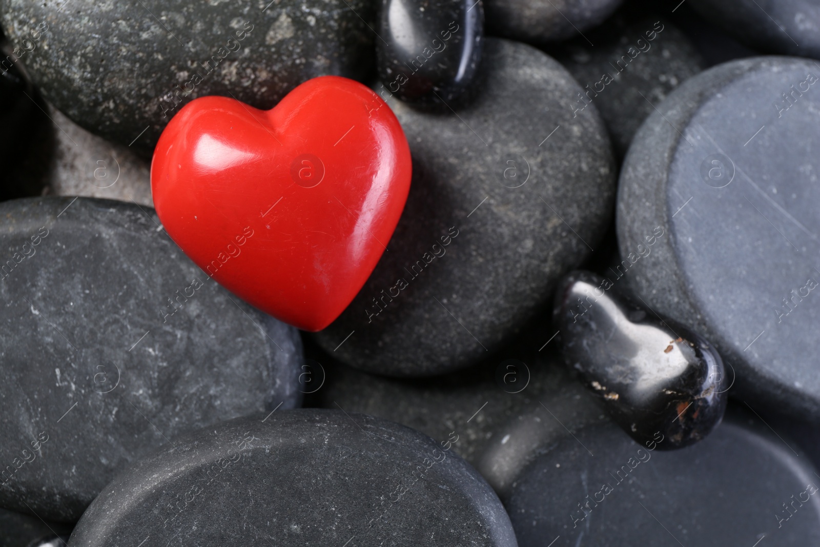 Photo of Red decorative heart on pebble stones, above view