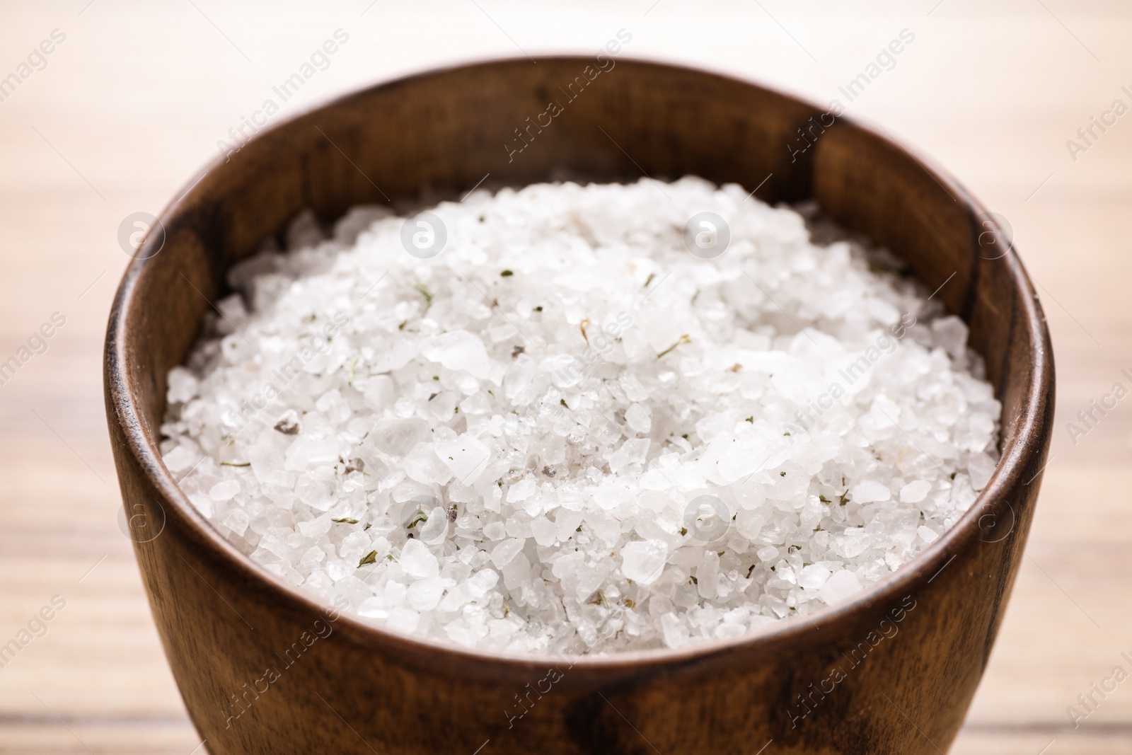 Photo of White sea salt for spa scrubbing procedure on wooden table, closeup