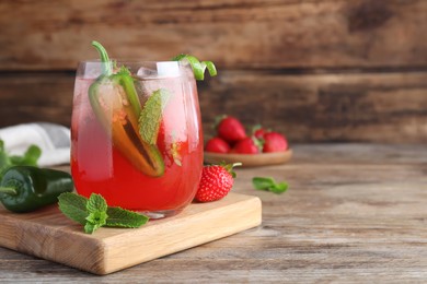 Spicy strawberry cocktail with jalapeno and mint on wooden table, space for text