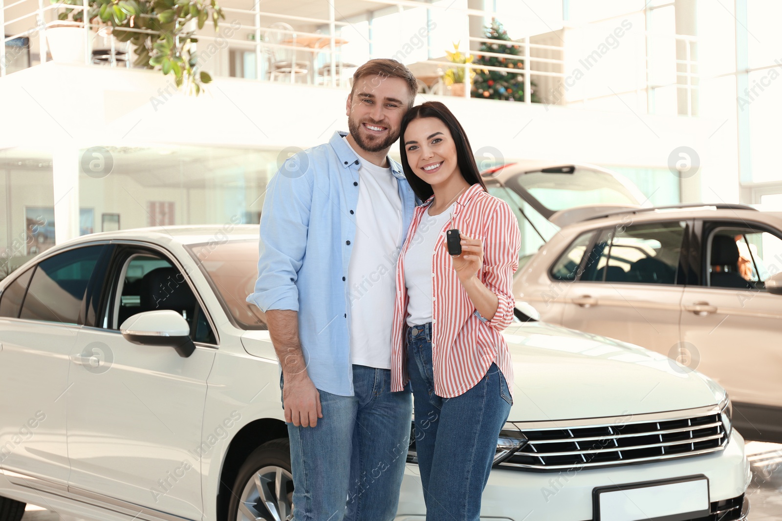 Photo of Happy couple with car key in modern auto dealership