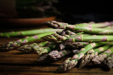 Photo of Fresh raw asparagus on wooden table, closeup