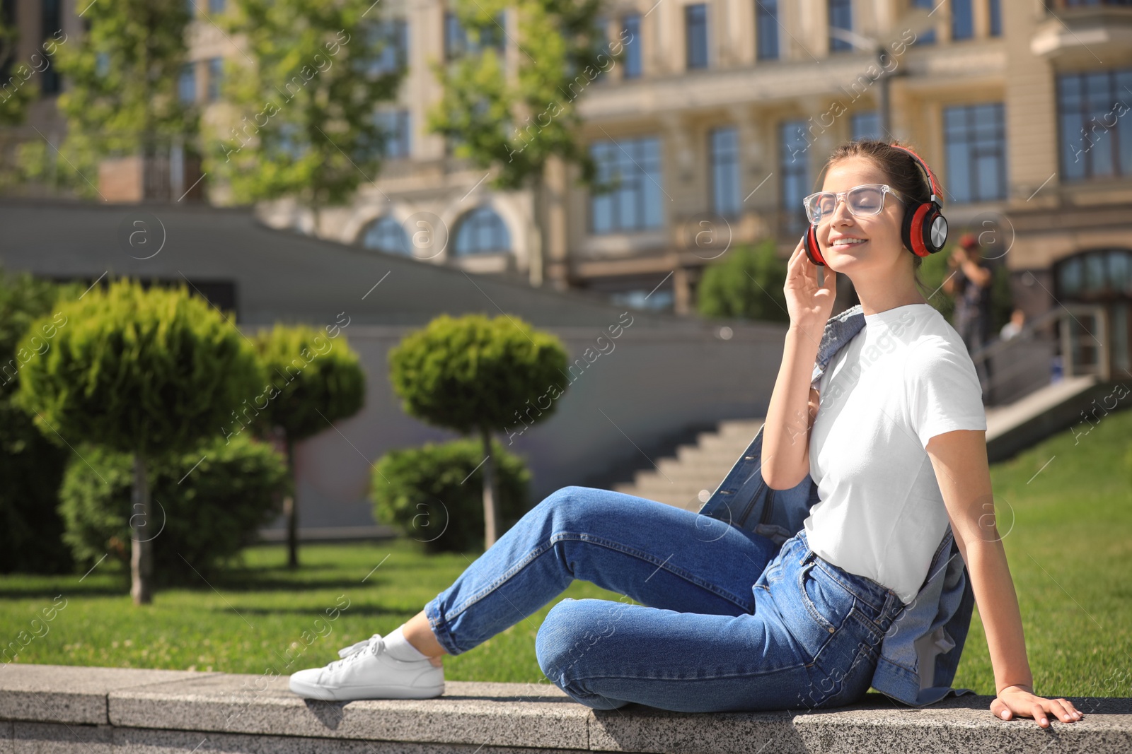 Photo of Young woman with headphones listening to music on city street. Space for text