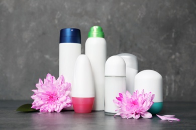 Photo of Different deodorants and flowers on table. Personal hygiene