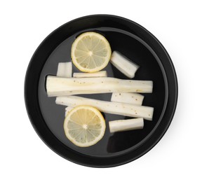 Photo of Bowl with water, fresh raw salsify roots and lemon slices isolated on white, top view