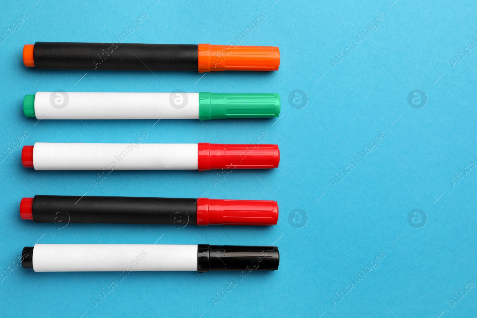 Photo of Bright color markers on light blue background, flat lay. Space for text