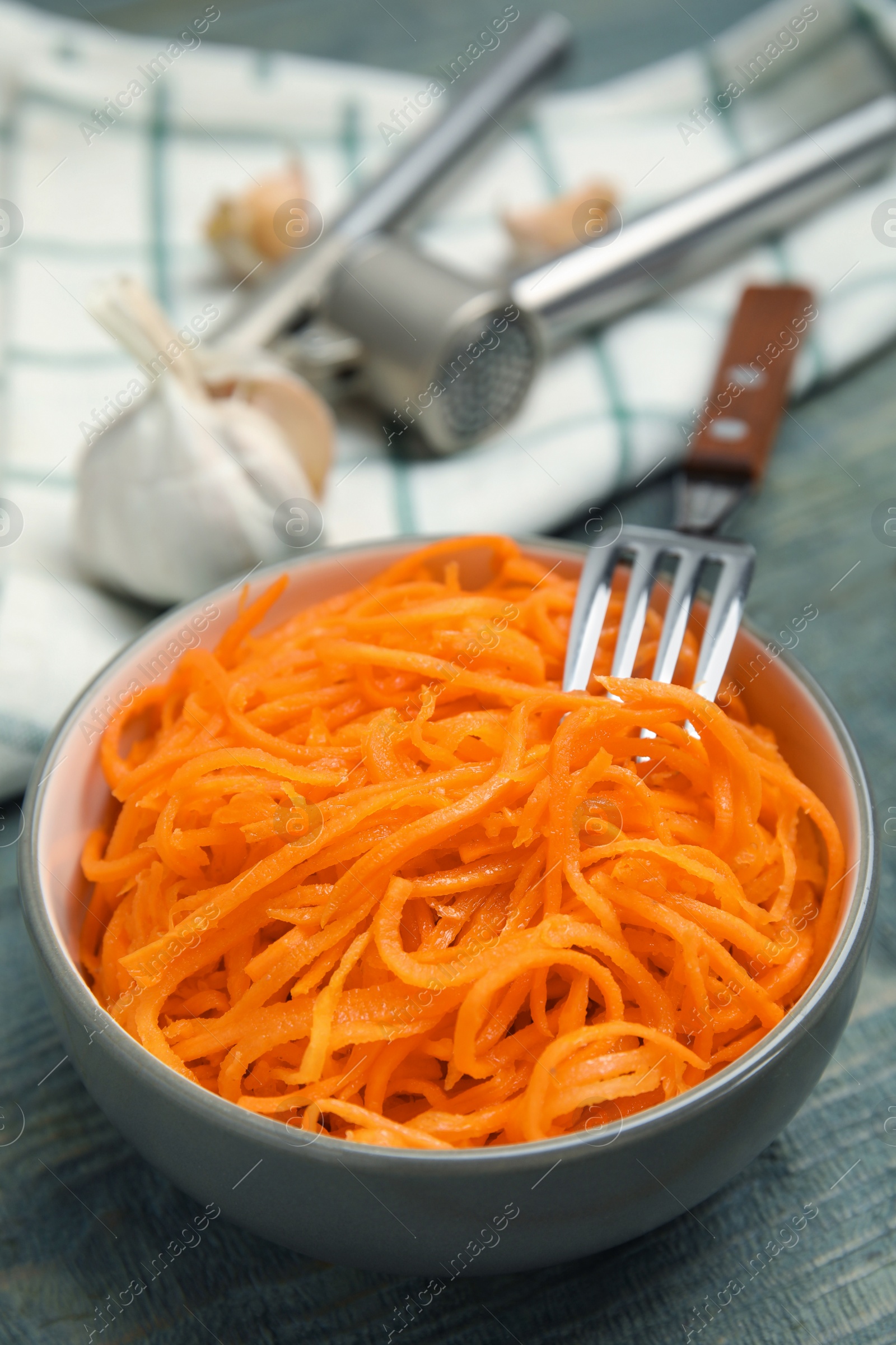 Photo of Delicious Korean carrot salad in bowl on blue wooden table