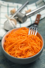 Photo of Delicious Korean carrot salad in bowl on blue wooden table