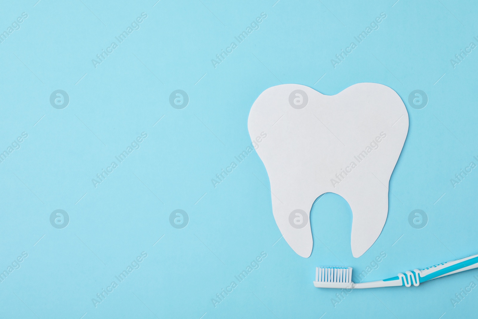 Photo of Paper tooth cutout and brush on color background, flat lay with space for text. Professional dentist