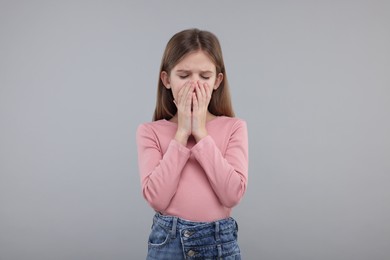Photo of Sick girl coughing on gray background. Cold symptoms