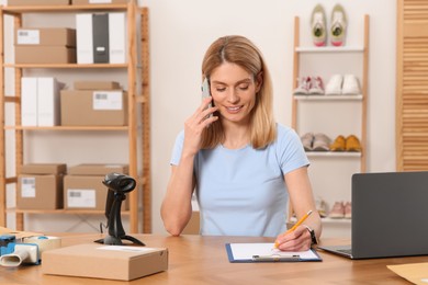 Photo of Seller talking on phone while working in office. Online store