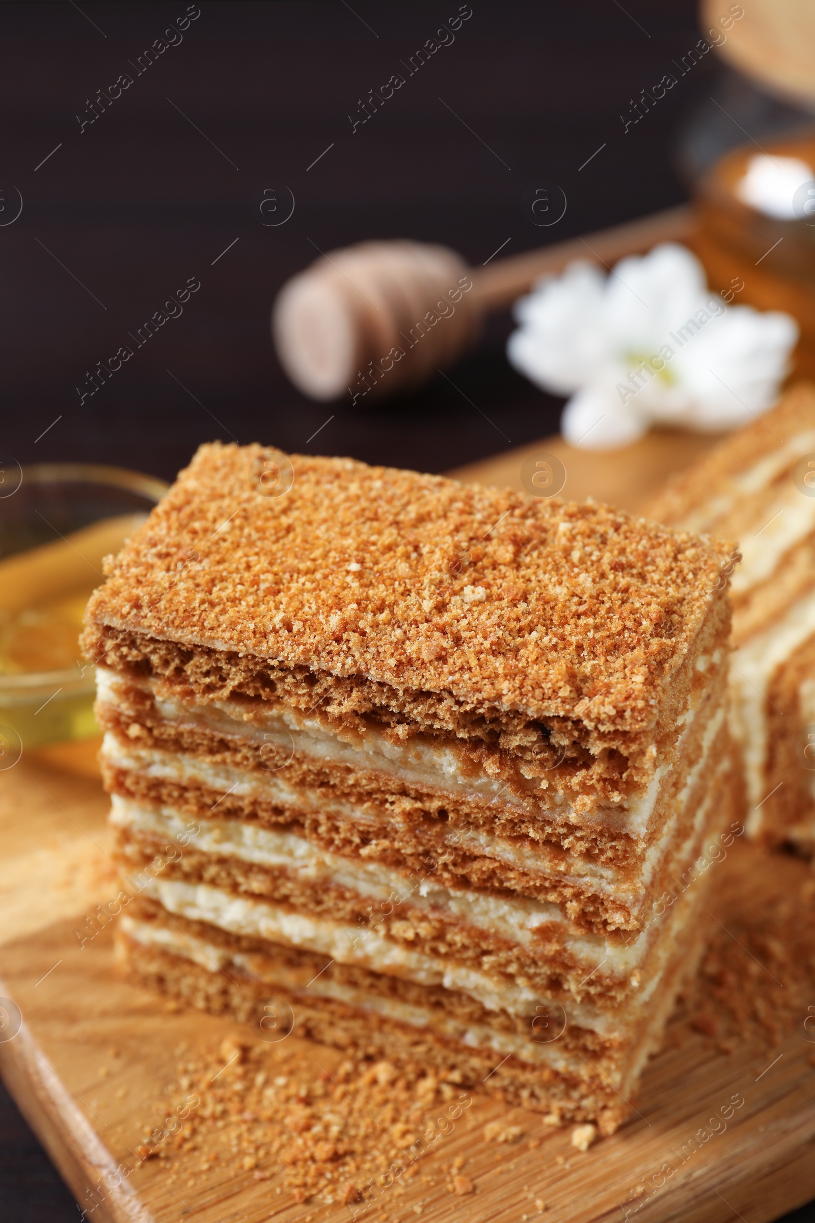 Photo of Delicious layered honey cake served on wooden board, closeup