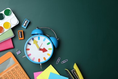 Photo of Flat lay composition with alarm clock and different stationery on green chalkboard, space for text. School time