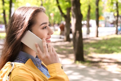 Photo of Young woman talking by phone outdoors on sunny day