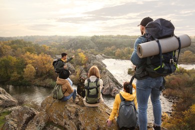 Photo of Group of friends with backpacks enjoying beautiful view near mountain river