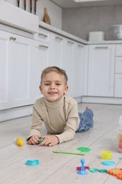 Photo of Cute little boy playing on warm floor in kitchen. Heating system