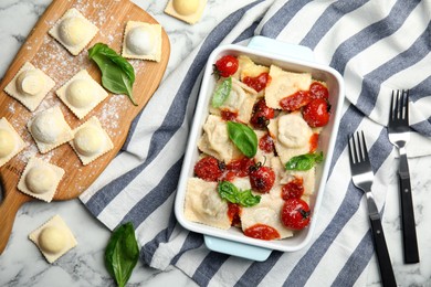 Photo of Raw and cooked ravioli with tomato sauce on white marble table, flat lay