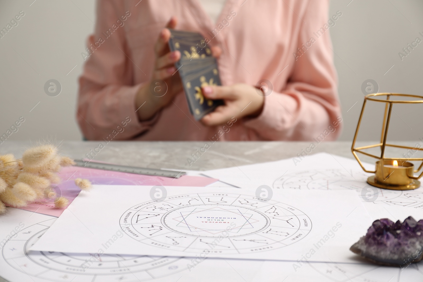 Photo of Zodiac wheels for astrological predictions on table, selective focus. Woman with tarot cards, closeup
